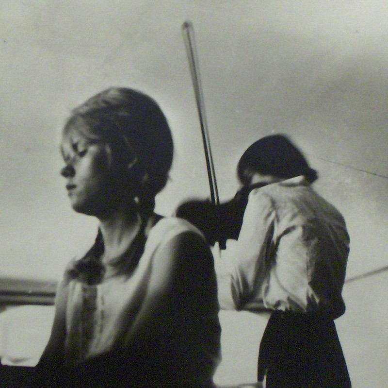Czarno-białe zdjęcie. Na pierwszym planie J. Tyszko grająca na fortepianie. Za nią A. Marczyńska, grająca na skrzypcach.