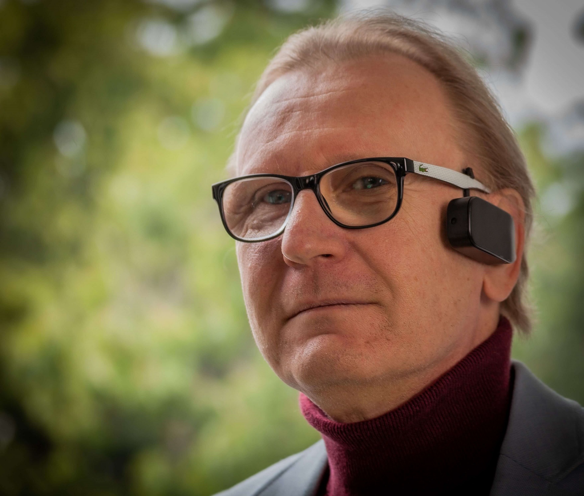 Man with glasses and Toucan Eye by his ear