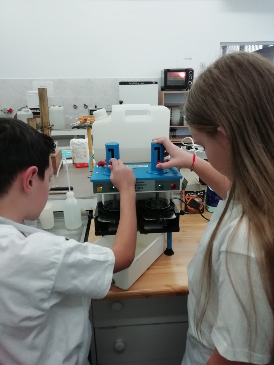 Laboratory. Two children, a boy and a girl, start up a specialized centrifuge