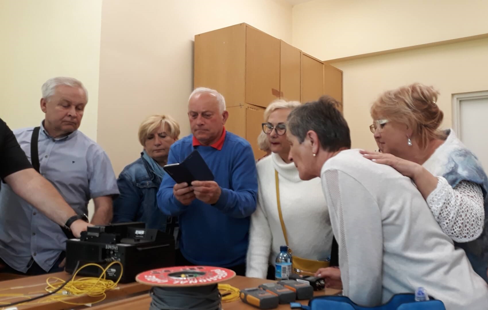 Classes for seniors at the Faculty of Electrical Engineering. The group, leaning over the engineering table, listens to the information read with interest. Coils of cables and specialized equipment on the table