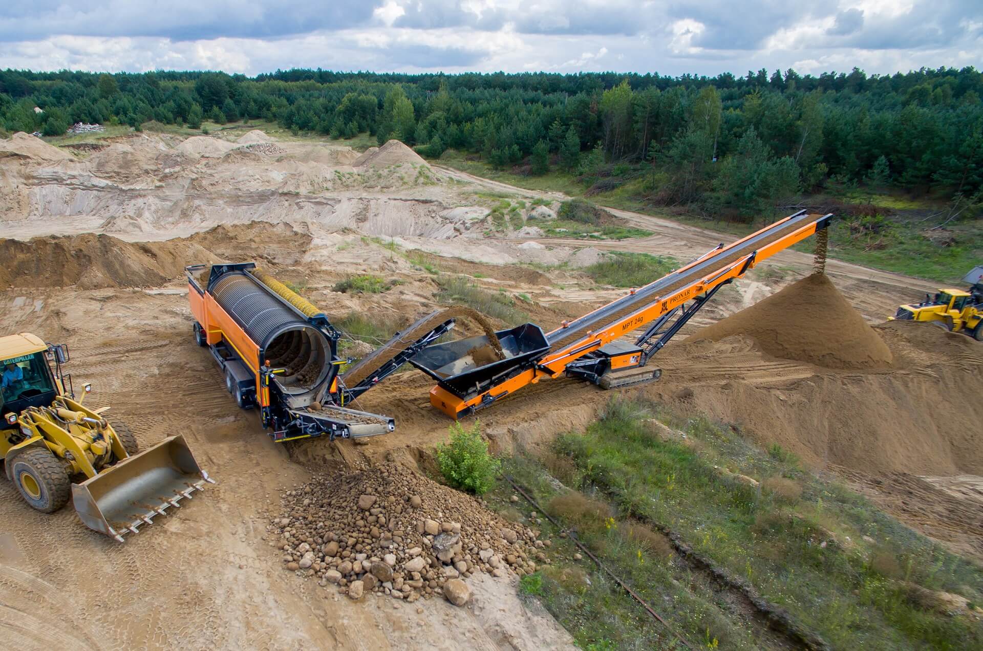Mobile Belt Conveyor MPT 24g. The height-adjustable conveyor belt runs on caterpillars in the area of ​​an opencast mine. Next to the fraction divider