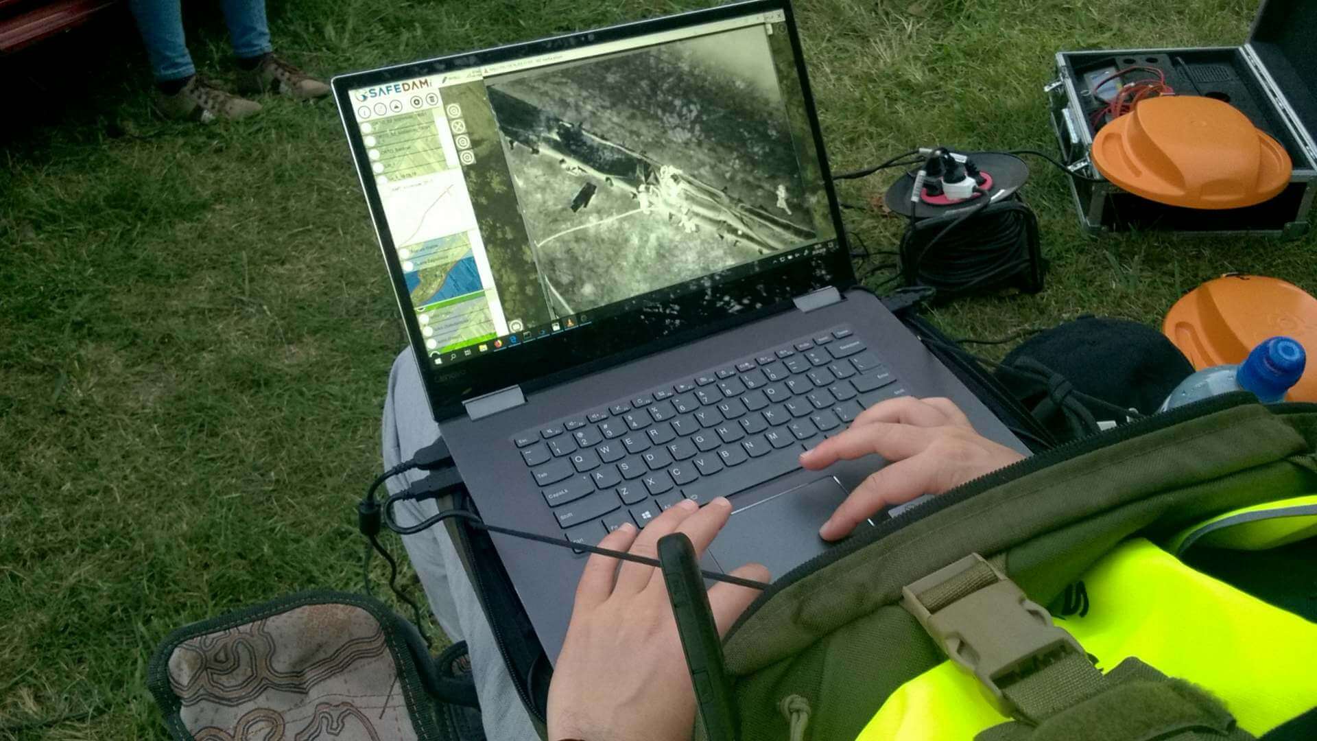 A man in the field browses data from the SAFEDAM system on a laptop