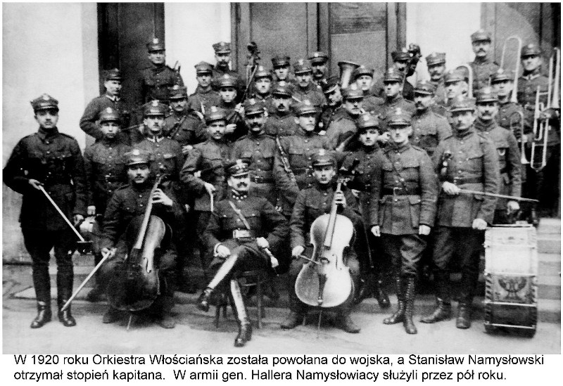 Orkiestra Włościańska ubrana w mundury wojskowe, muzycy trzymają swoje instrumenty, po środku siedzi Karol Namysłowski. W tle biały budynek z dużymi podwójnymi drzwiami