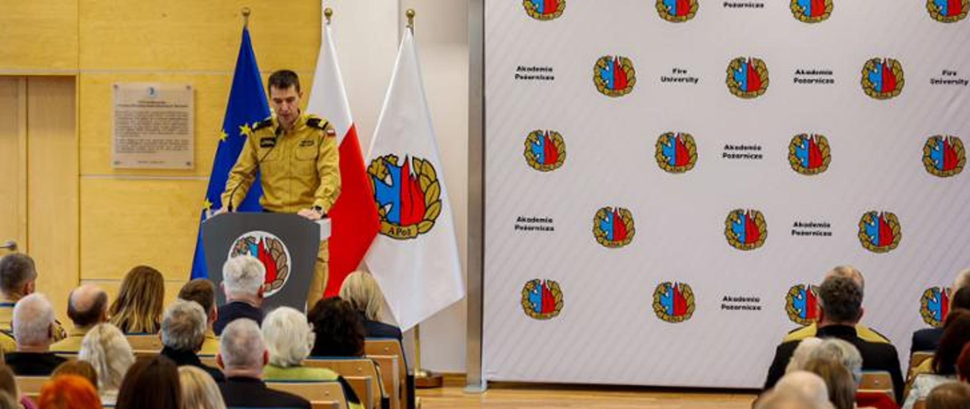 komendant główny państwowej straży pożarnej nadbrygadier doktor inżynier Mariusz Feltynowski ubrany w mundur służbowy stoi przy mównicy na sali wykładowej pełnej uczestników konferencji