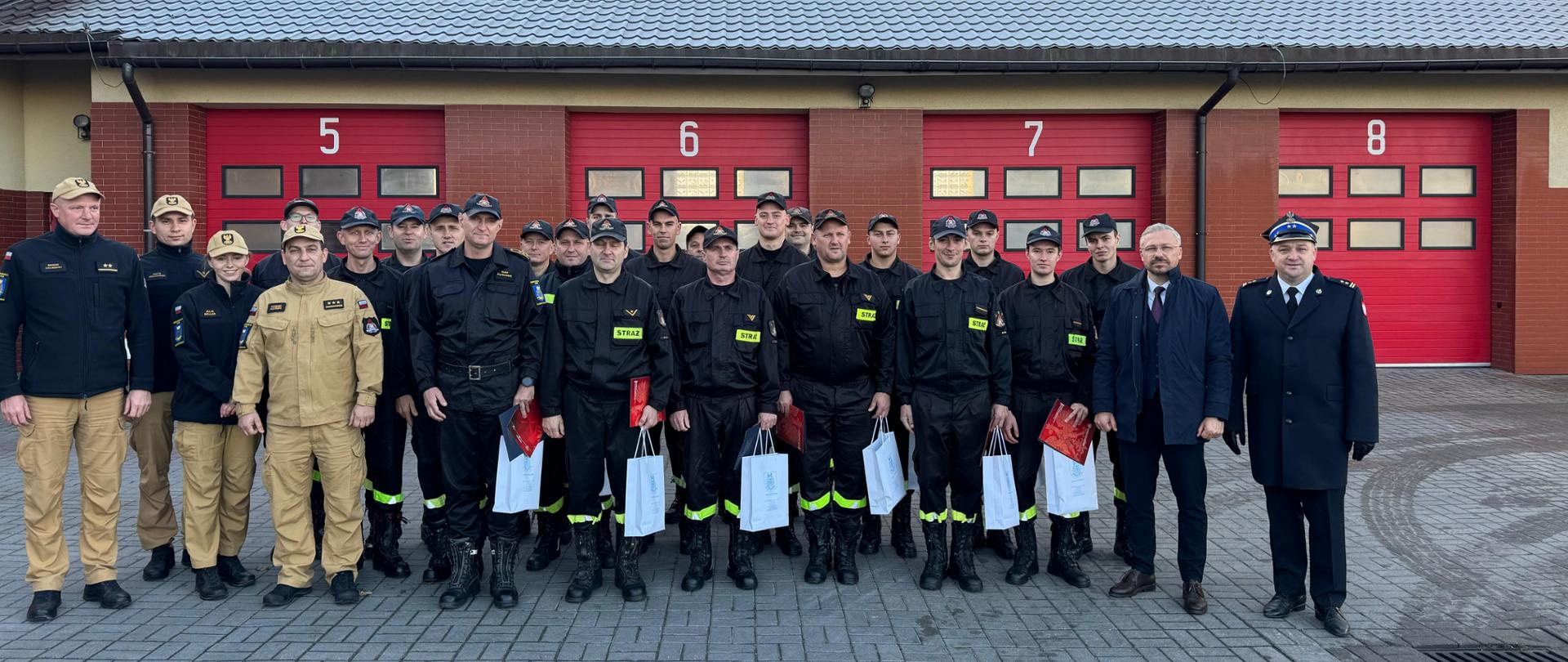 Na pierwszym planie widoczna jest grupa strażaków stojących w szeregu obok nich, również stoją Starosta Rypiński, Komendant Powiatowy Państwowej Straży Pożarnej w Rypinie oraz Zastępca Komendanta. W tle można dostrzec garaże komendy.