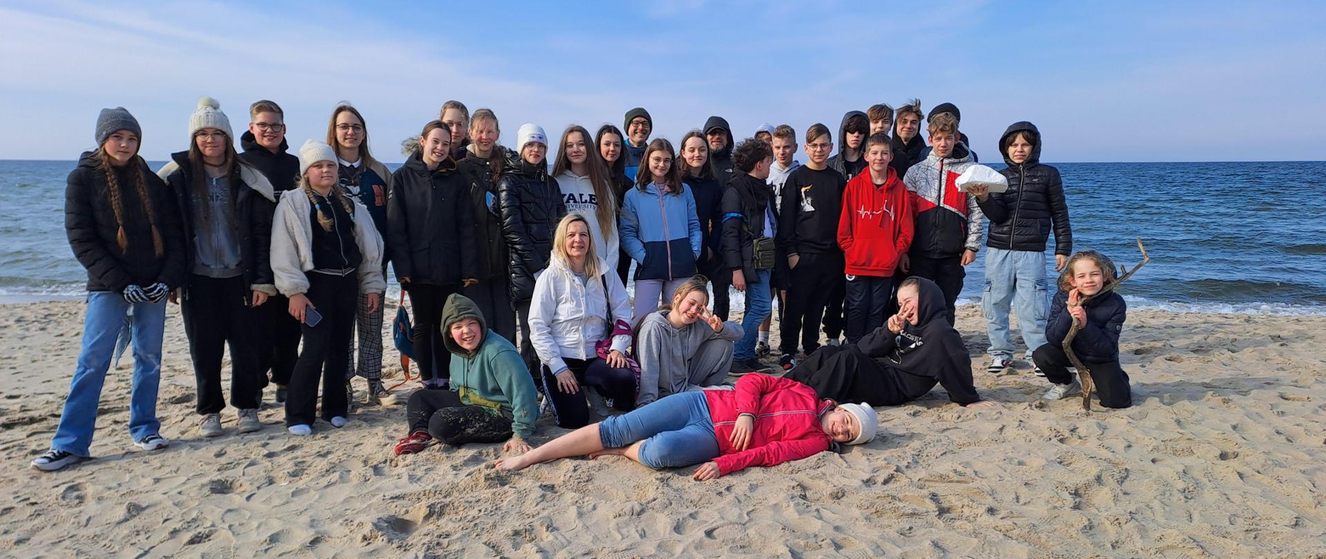 Na plaży, na tle morza Bałtyckiego pozują do zdjęcia uczestnicy obozu kondycyjnego wraz z opiekunami.
