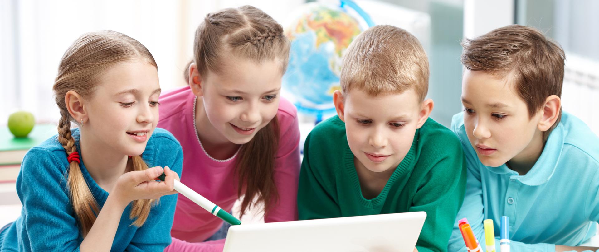 Portrait of smart schoolgirls and schoolboys looking at the laptop in classroom