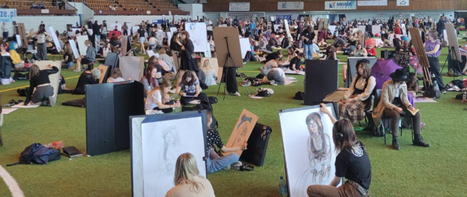 Fotografia z 27. Międzynarodowego Festiwalu Rysowania w Zabrzu przedstawiająca wnętrze MOSiR i rozsianych rysujących uczestników.