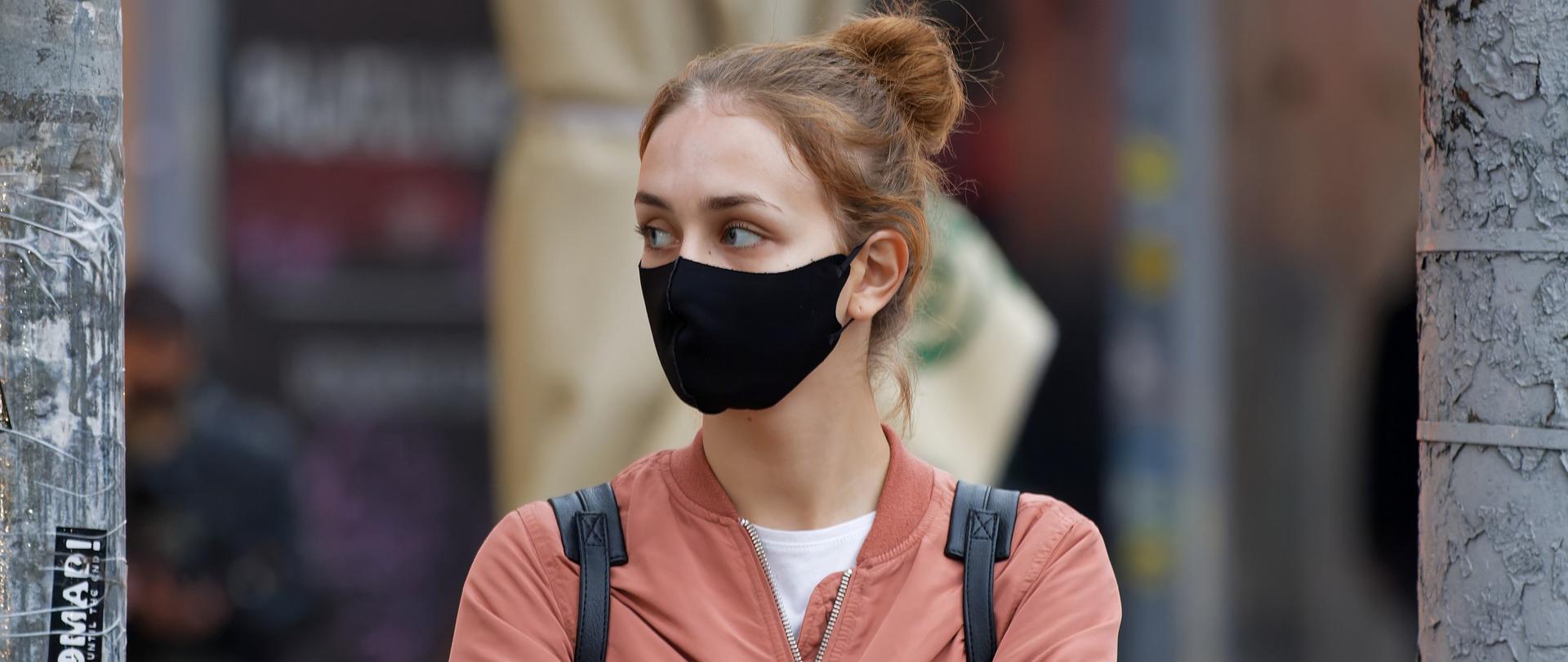 kobieta stojąca na ulicy w maseczce ochronnej na twarzy