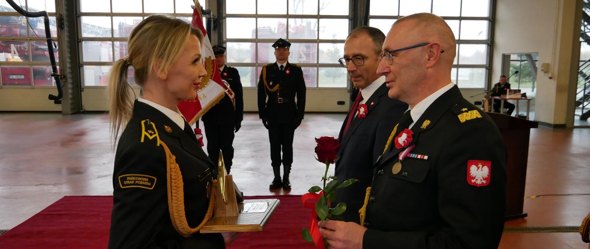 Lubuski komendant wojewódzki wręcza Lbuski Toporek funkcjonariuszcze mł. asp. Jolancie Marcinkowskiej. W tle poczet sztandarowy PSP.