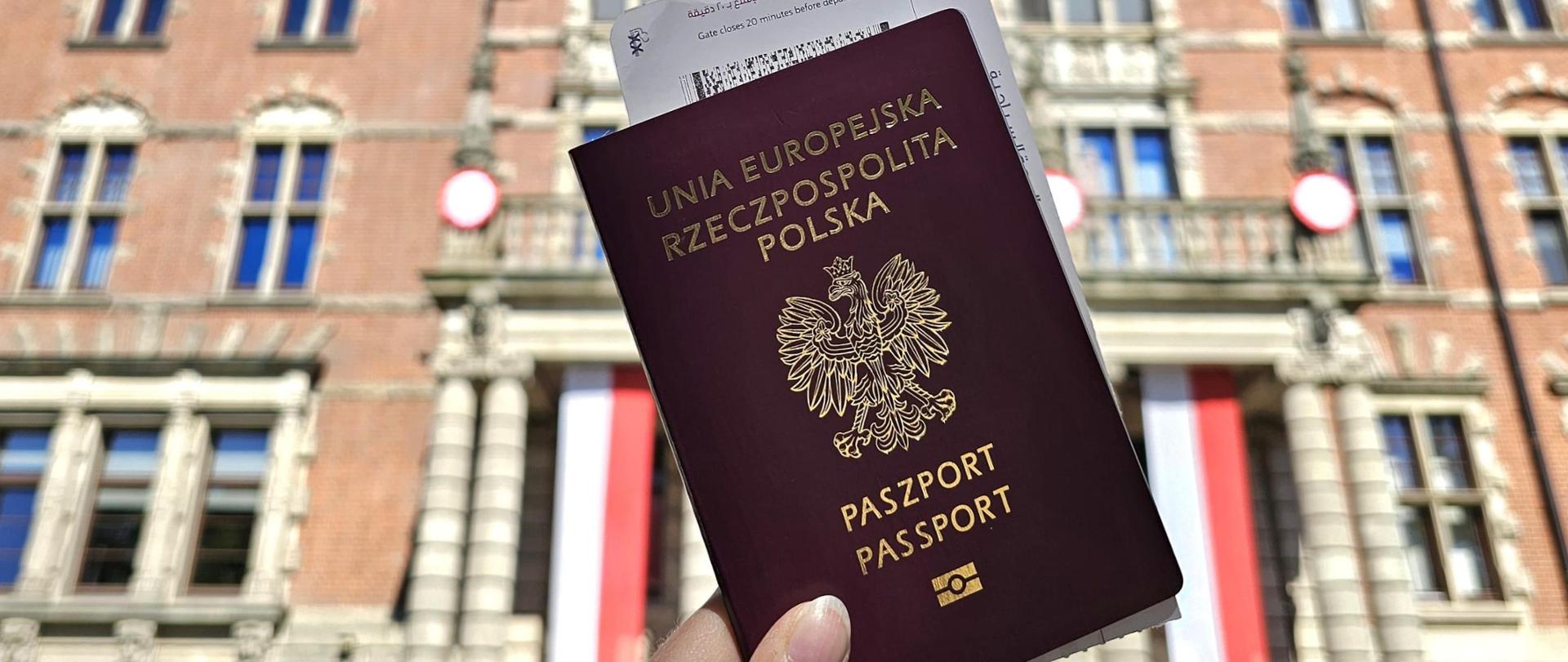 paszport trzymany w dłoni na tle wejścia głównego do Urzędu Wojewódzkiego w Szczecinie 