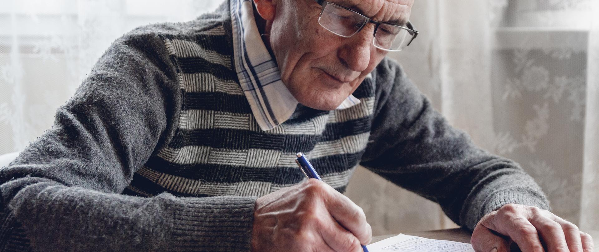 Elderly man solves sudoku or a crossword puzzle to slow the progression of Alzheimer's disease