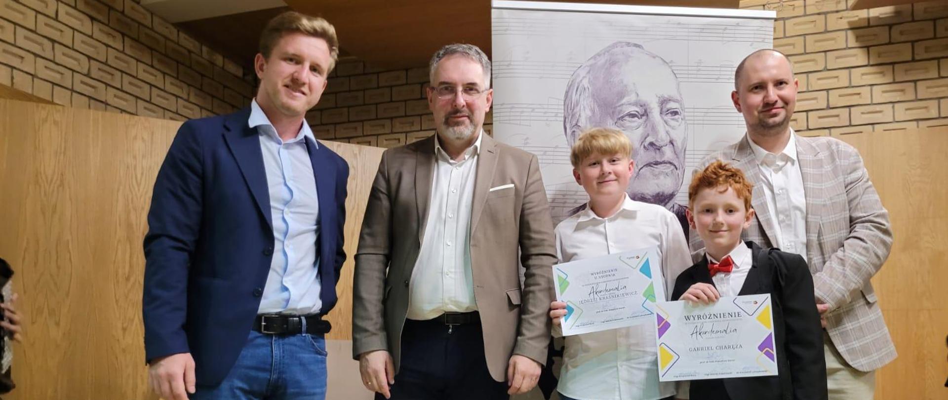 Trójka mężczyzn stoi z dwójką uczniów, którzy trzymają dyplomy za osiągnięcia na Ogólnopolskim Konkursie Akordeonowym w Pruszkowie zdobywają WYRÓŻNIENIA! - 11 maja 2024