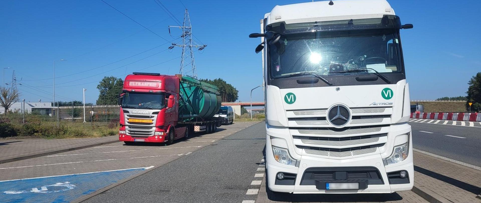 Na zdjęciu widoczne są dwa zaparkowane samochody ciężarowe, za nimi pojazd ITD