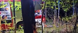 Na zdjęciu widoczny samochód ratowniczo-gaśniczy z którego rozwinięta jest linia główna. Obok samochodu znajduje się strażak.