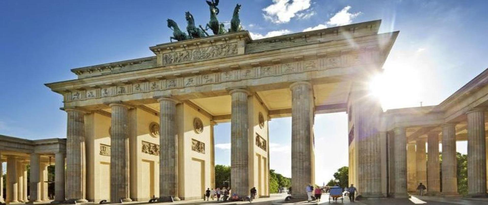 Zdjęcie Bramy Brandenburskiej zabytkowej budowli w Berlinie, zaprojektowanej przez niemieckiego architekta Carla Gottharda Langhansa. Zdjęcie zrobione w pogodny dzień.