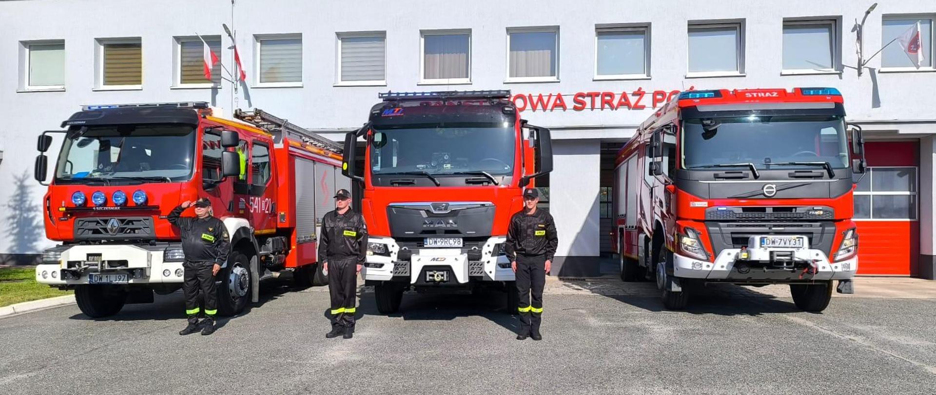 Strażacy na tle samochodów pożarniczych