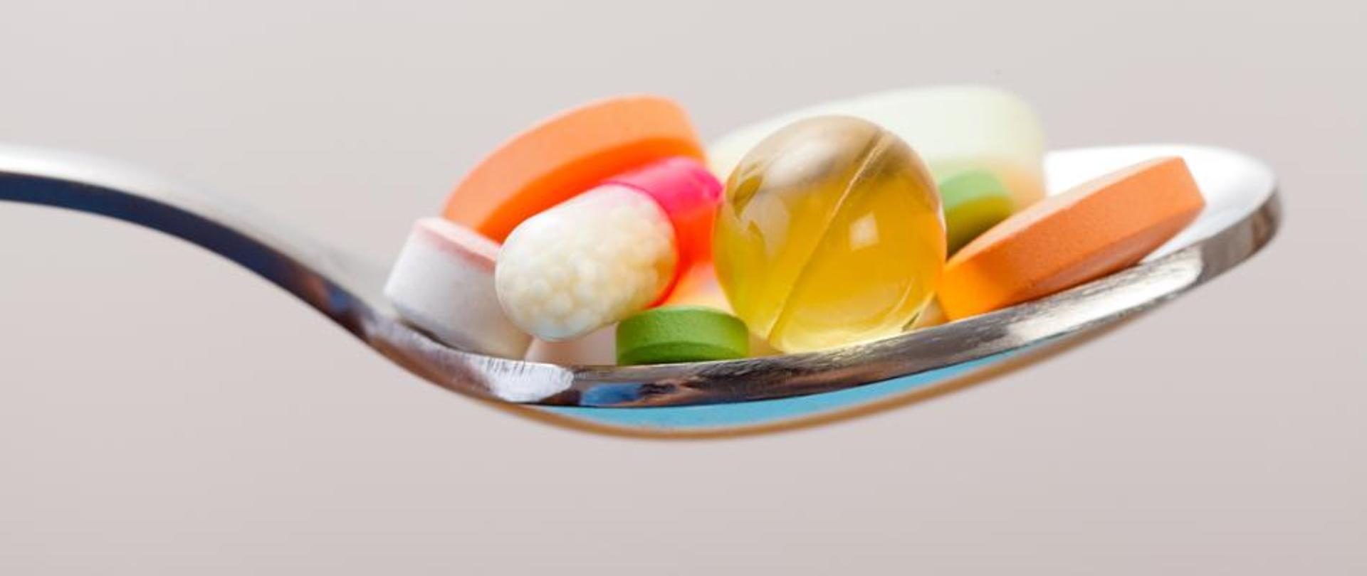 Zdjęcie na którym jest łyżka z tabletkami w różnych kolorach