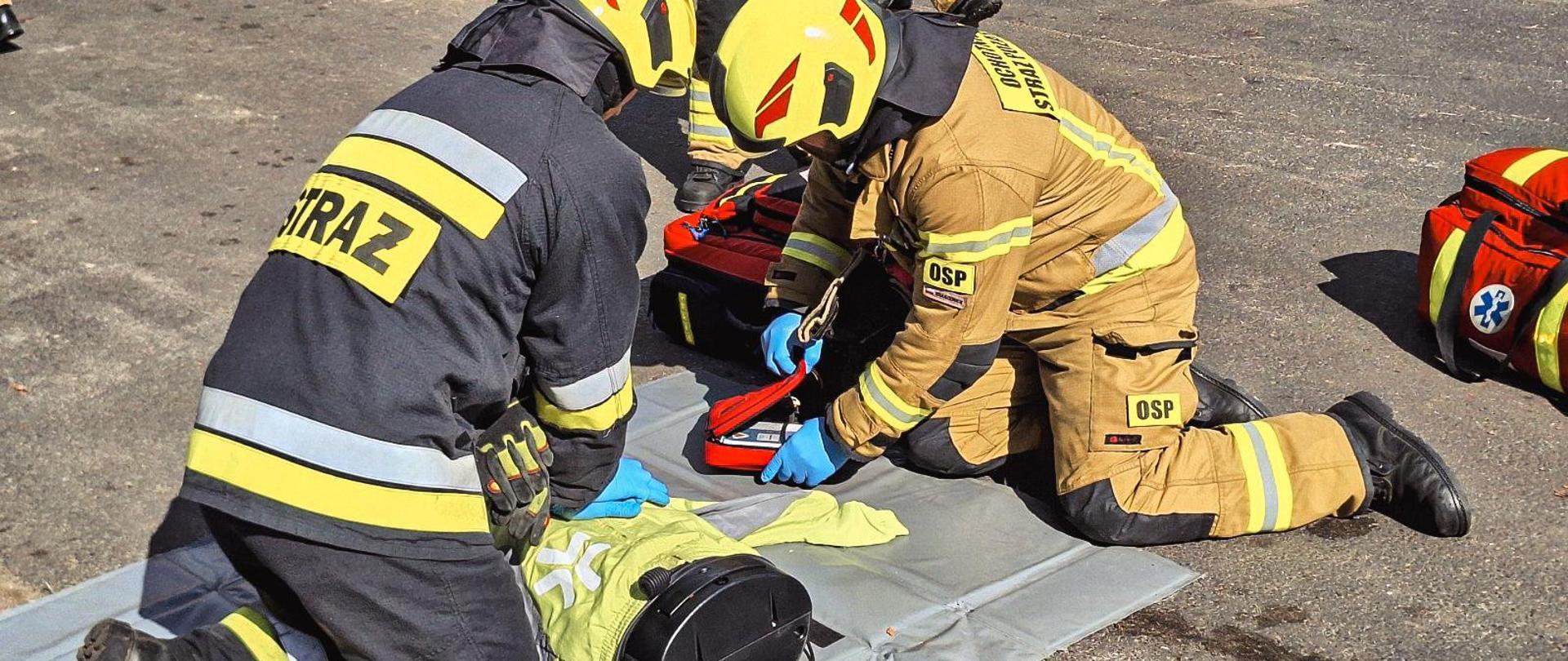Strażacy w trakcie wykonywania resuscytacji krążeniowo-oddechowej na manekinie.