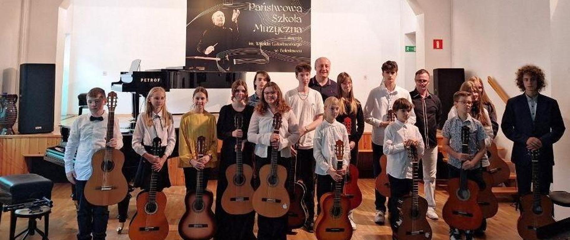 Zdjęcie przedstawiające wykonawców popisu klasy gitary Sebastiana Środy i Bartłomieja Filipowicza, który odbył się 22 maja 2024 r. w auli szkoły.