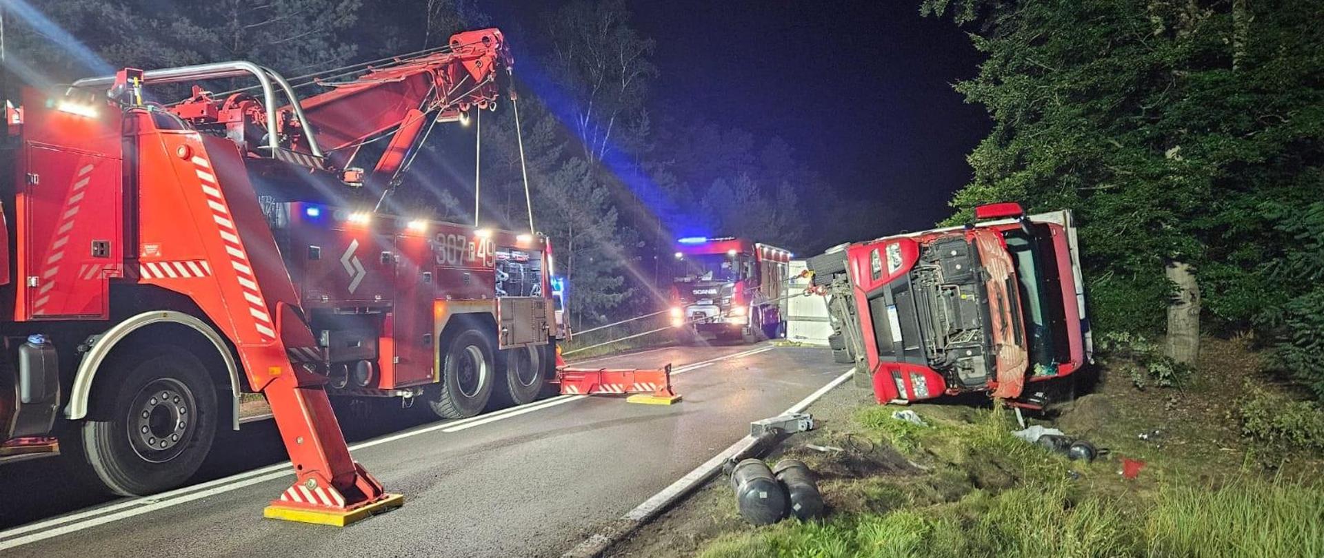 Ciężarówka podnoszona przez dźwig strażacki.