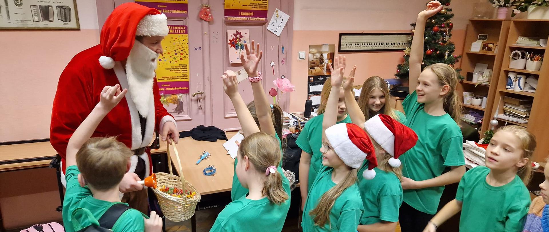 Mikołaj rozdaje słodycze dziewczynkom z zespołu rytmicznego ubranym w zielone koszulki