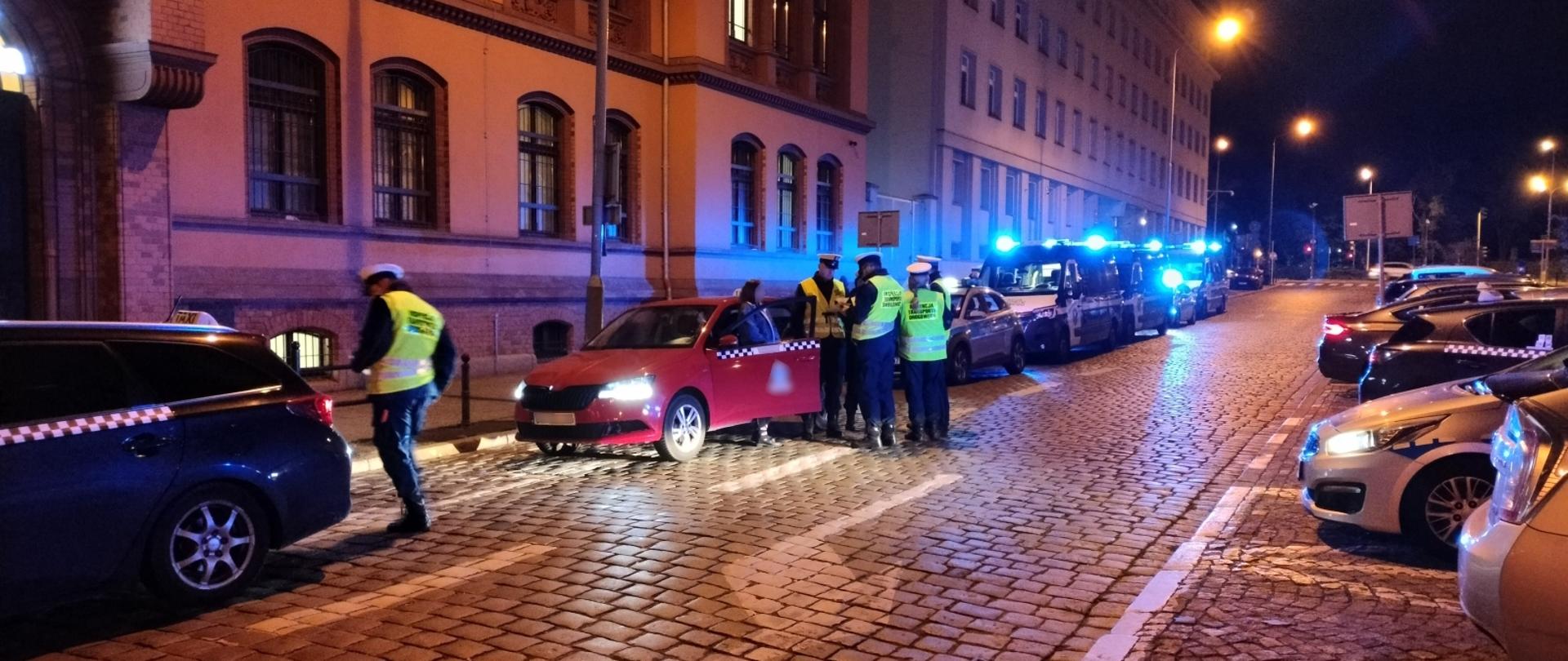 Rząd pojazdów w tym taxówki, samochody Policji oraz ITD.