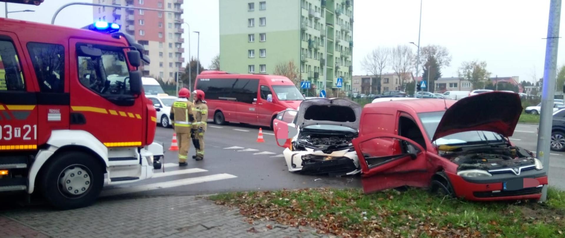 Zdjęcie przedstawia ulicę Grunwaldzką: z lewej strony stoi samochód pożarniczy zaś po lewej widać oba zniszczone w skutek zderzenia pojazdy.