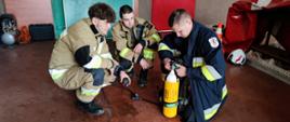 Garaż, strażacy ćwiczą obsługę aparatów oddechowych
