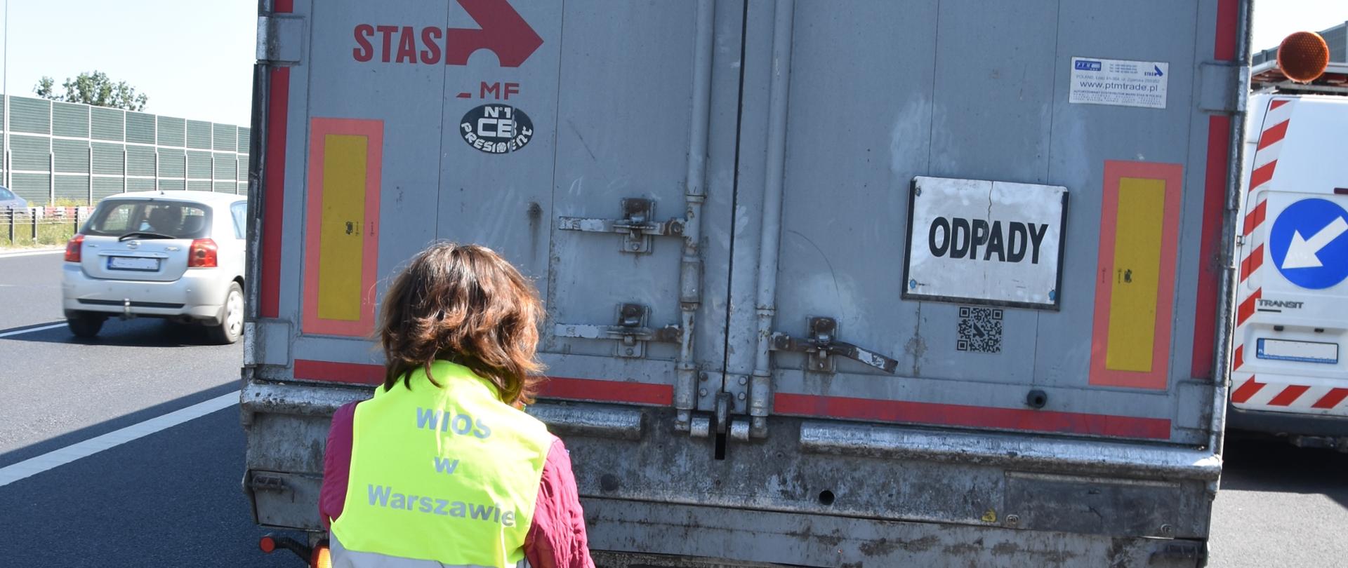 Inspektor Wojewódzkiego Inspektoratu Ochrony Środowiska w Warszawie kontroluje samochód ciężarowy.