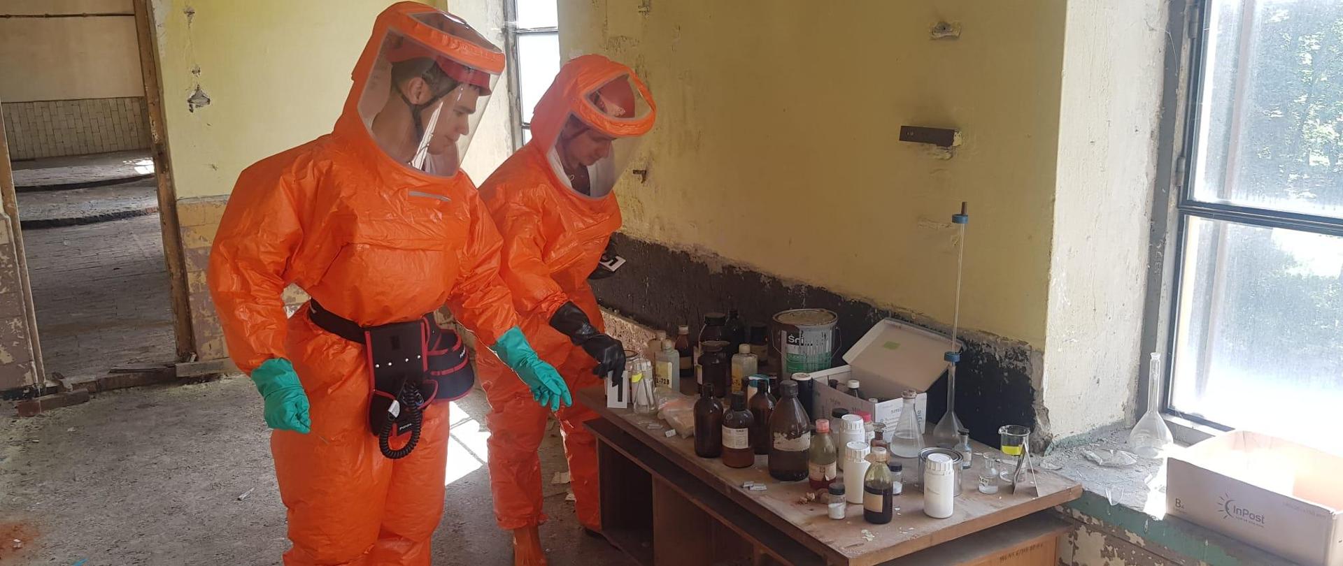 Zdjęcie przedstawia dwóch strażaków z Specjalistycznej Grypy Ratownictwa Chemiczno-Ekologicznego „Leżajsk” zabezpieczających materiał niebiezpieczny.