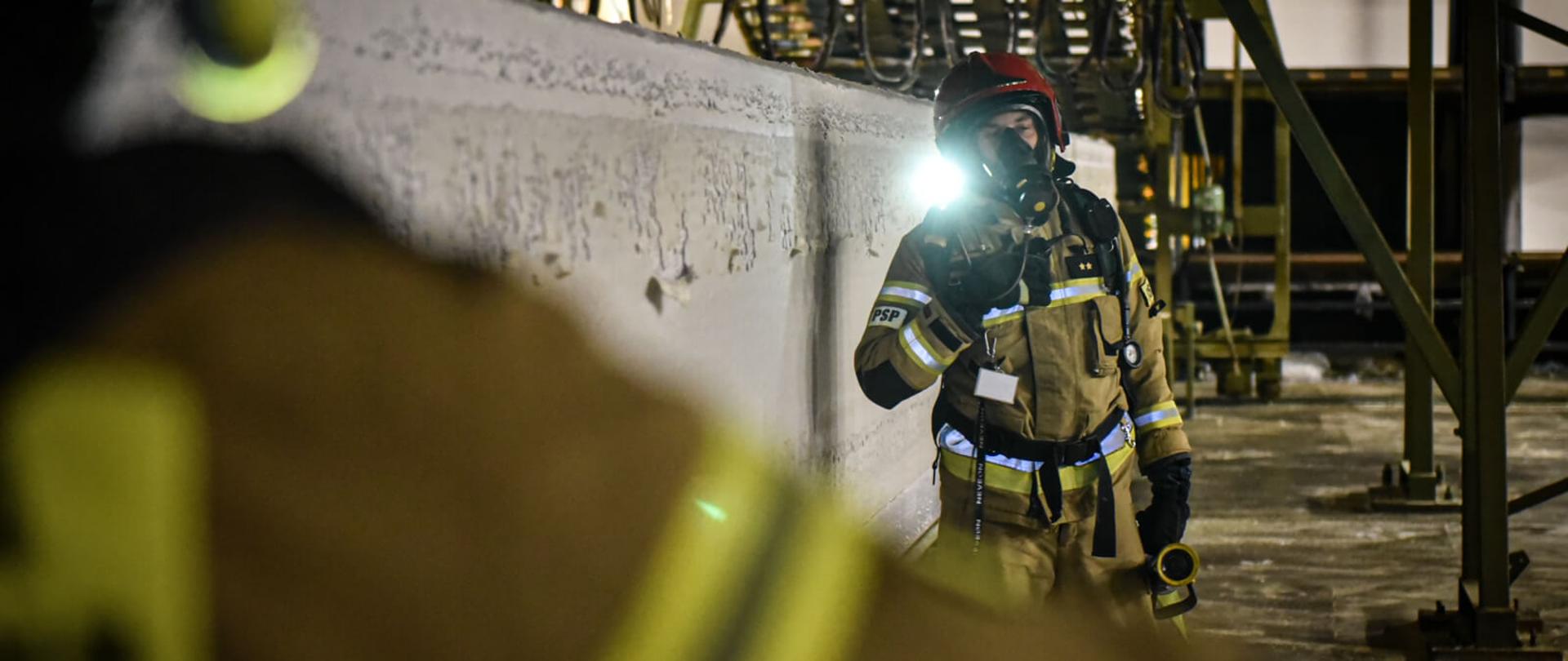 strażak w ubraniu bojowym w hali produkcyjnej zakładu