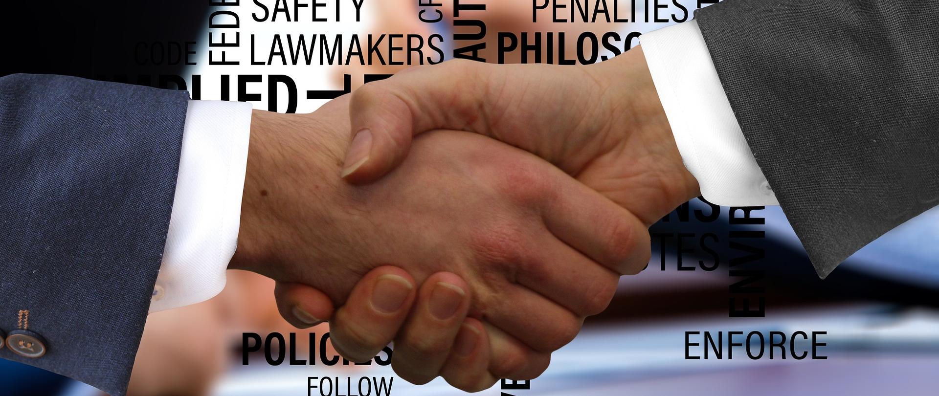 Na zdjęciu znajdują się dwie męskie dłonie, które się ściskają po podpisaniu umowy.