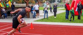 Na zdjęciu widoczny zawodnik w czarnej koszulce i czarnych spodenkach biegnący z piłką w ręku biorący udział w konkurencji slalom z piłką podczas XXXII Spartakiady Honorowych Dawców Krwi Polskiego Czerwonego Krzyża w Bobowej.