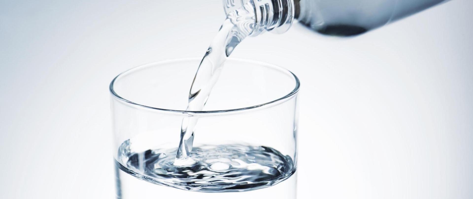 Na zdjęciu jest szklanka wody napełniona wodą z butelki.