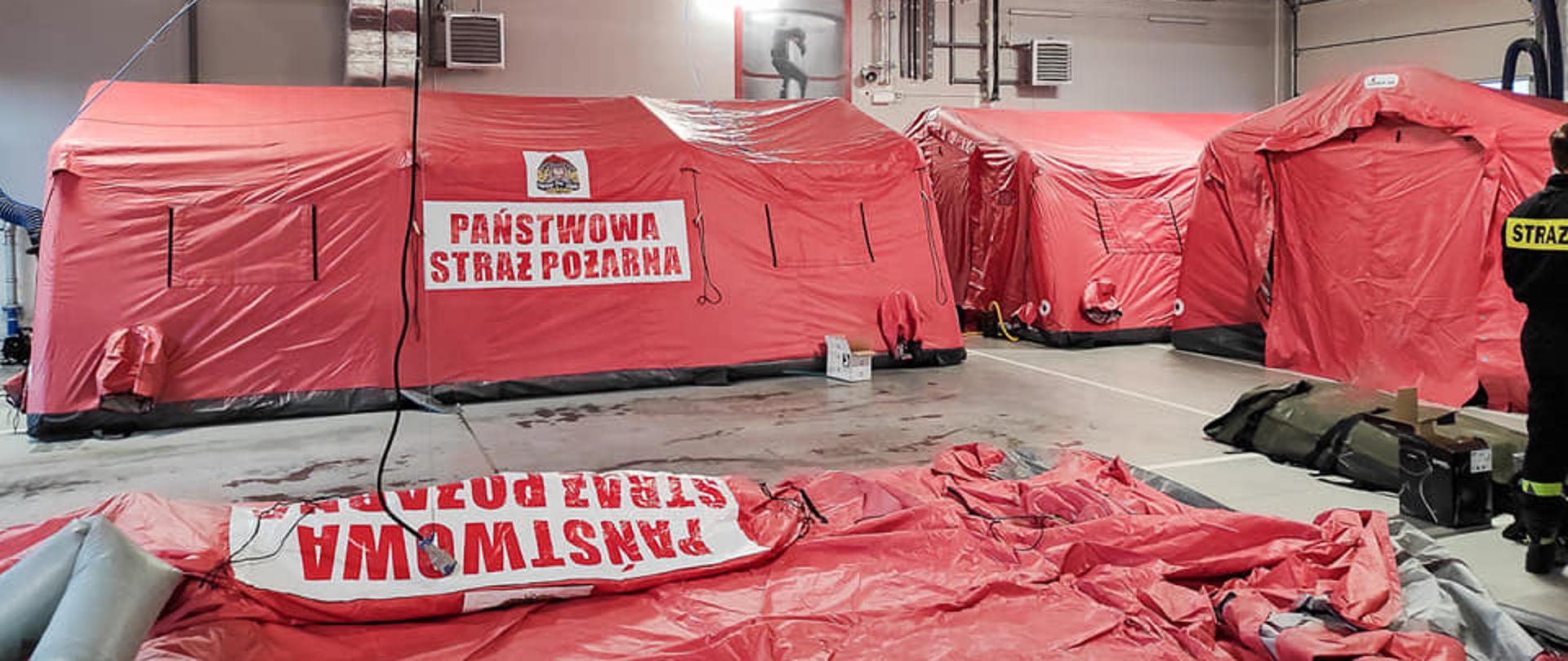 Zdjęcie przedstawia proces rozkładania nowych namiotów pneumatycznych na których znajduje się logo PSP oraz napis Państwowa Straż Pożarna. 