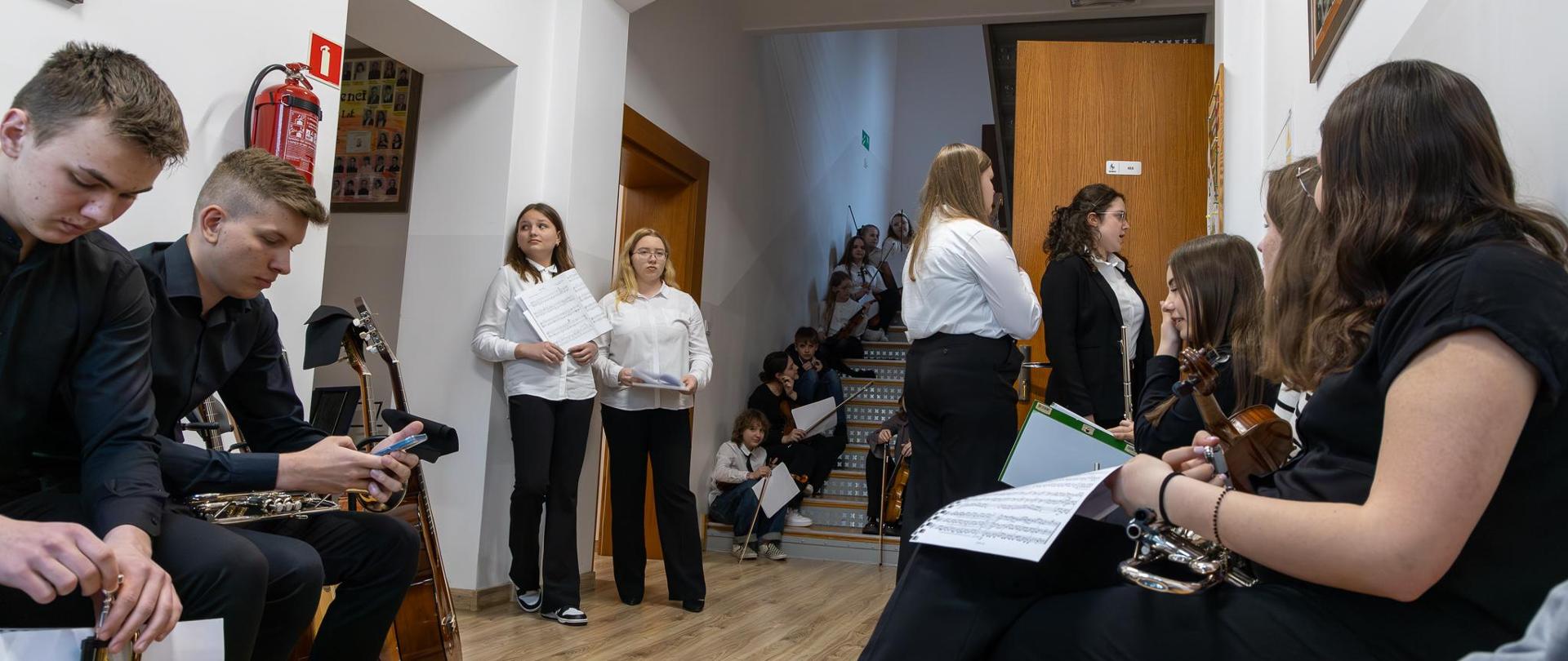 XVIII Szkolny Konkurs Zespołów Kameralnych. Uczestnicy konkursu na korytarzu przed aulą oczekują na swoje prezentacje.