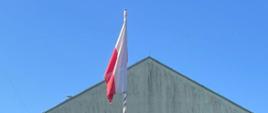 Widok na flagę Rzeczpospolitej Polskiej wciągniętej na maszt