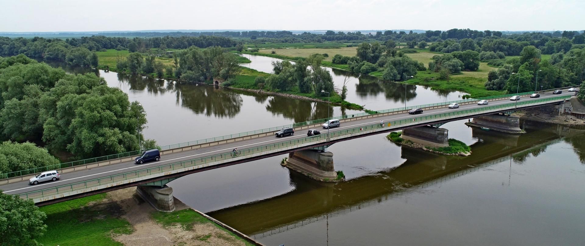 Na zdjęciu widać rzekę i biegnący nad nią most, po którym jadą samochody. W górnej części zdjęcia, za mostem, rzeka rozwidla się w dwóch kierunkach. Całość otoczona zielenią.