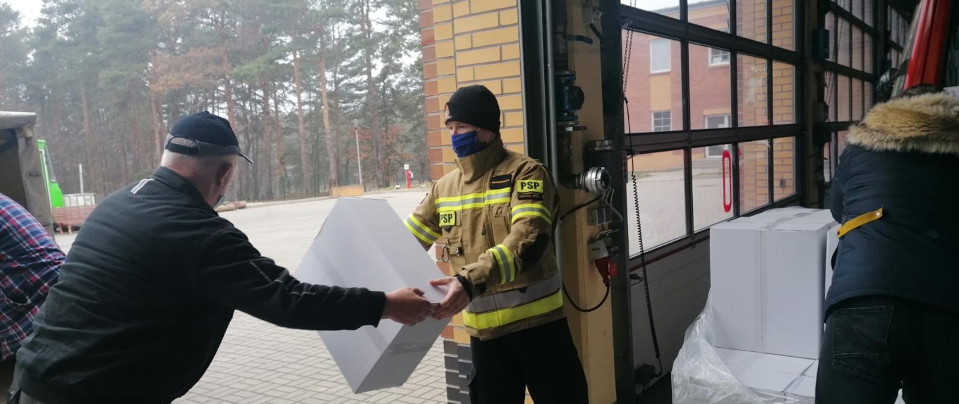 pomoc w transporcie i dystrybucji maseczek - strażacy przekazują kartony