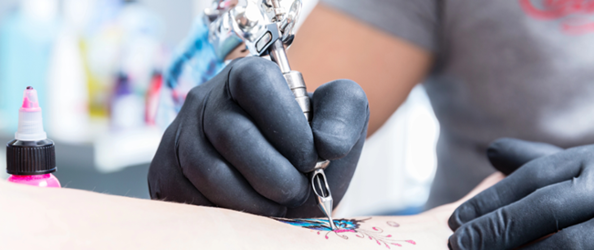 Zdjęcie przedstawia dłonie w rękawiczkach tatuujące wzór na ręku klienta