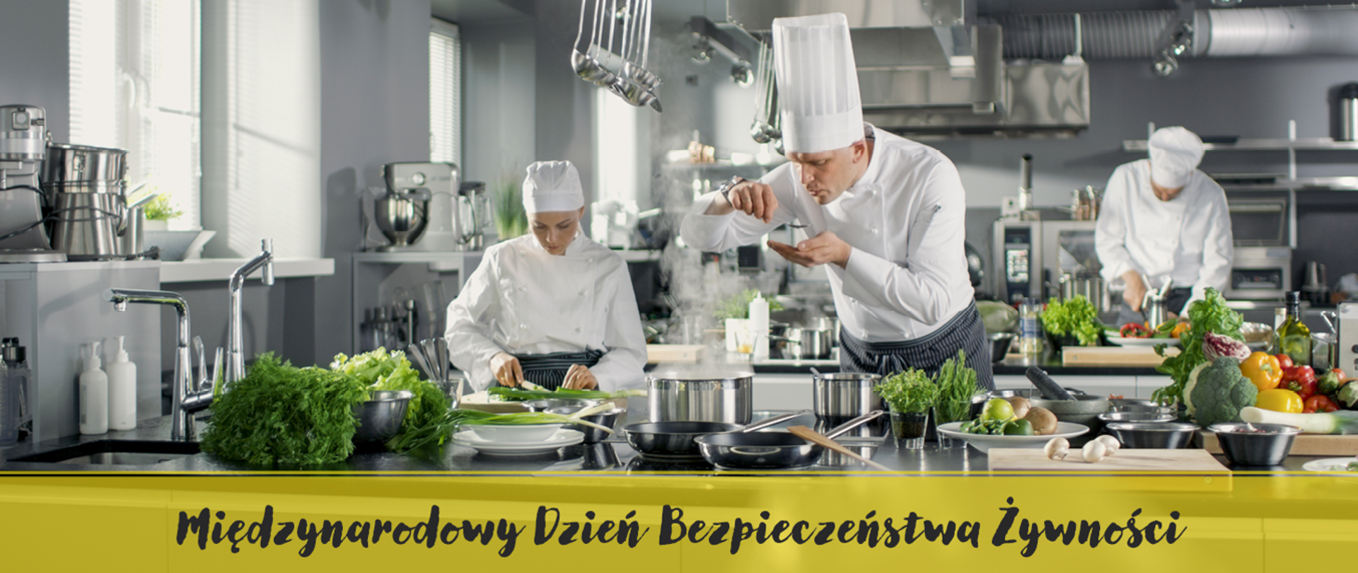 trzech kucharzy w białych fartuchach gotuje potrawy w dużej kuchni restauracyjnej, na dole napis: Międzynarodowy Dzień Bezpieczeństwa Żywności