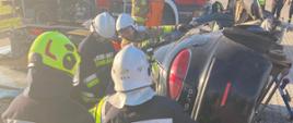 strażacy podczas założenia egzaminacyjnego w trakcie stabilizacji pojazdu przewróconego na bok