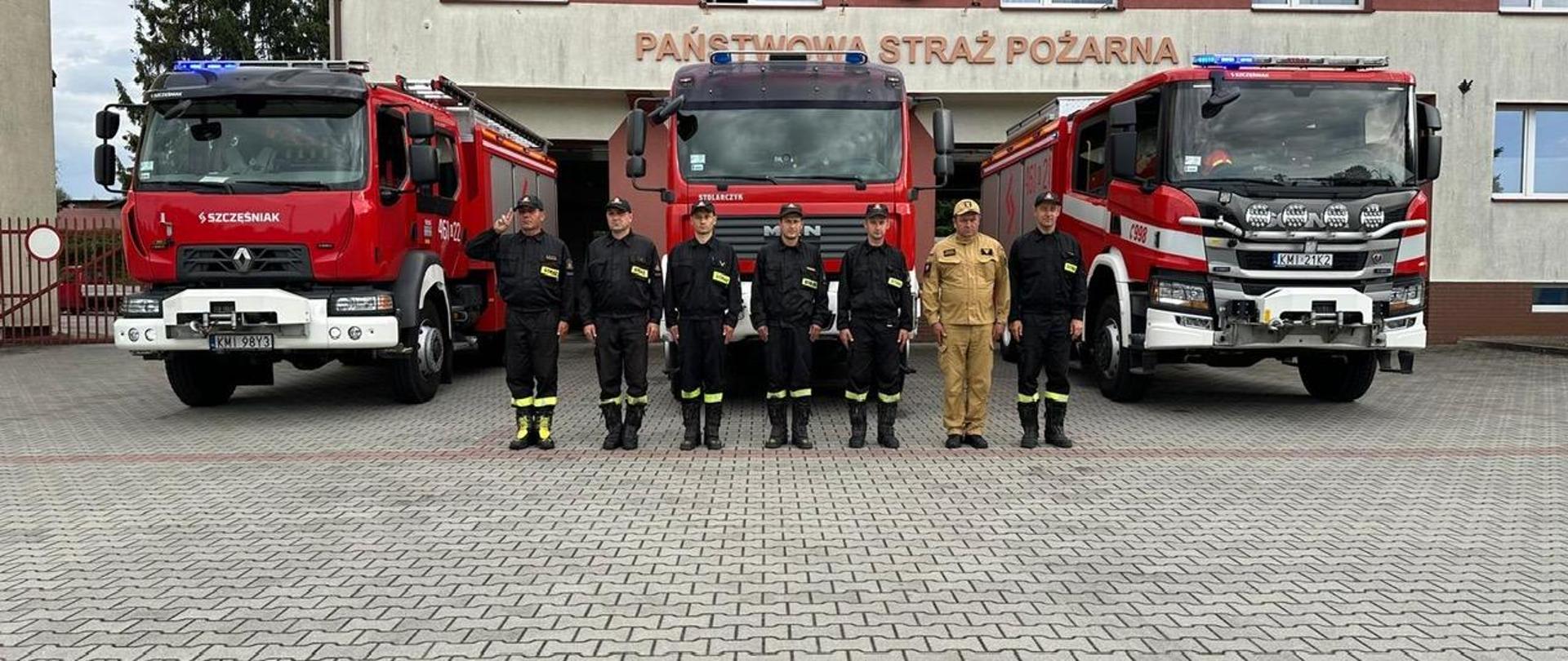 Na zdjęciu strażacy JRG Miechów oraz z tyłu wozy strażackie na tle budynku JRG 