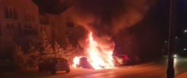 Zdjęcie przedstawia rozwinięty pożar dwóch samochodów osobowych