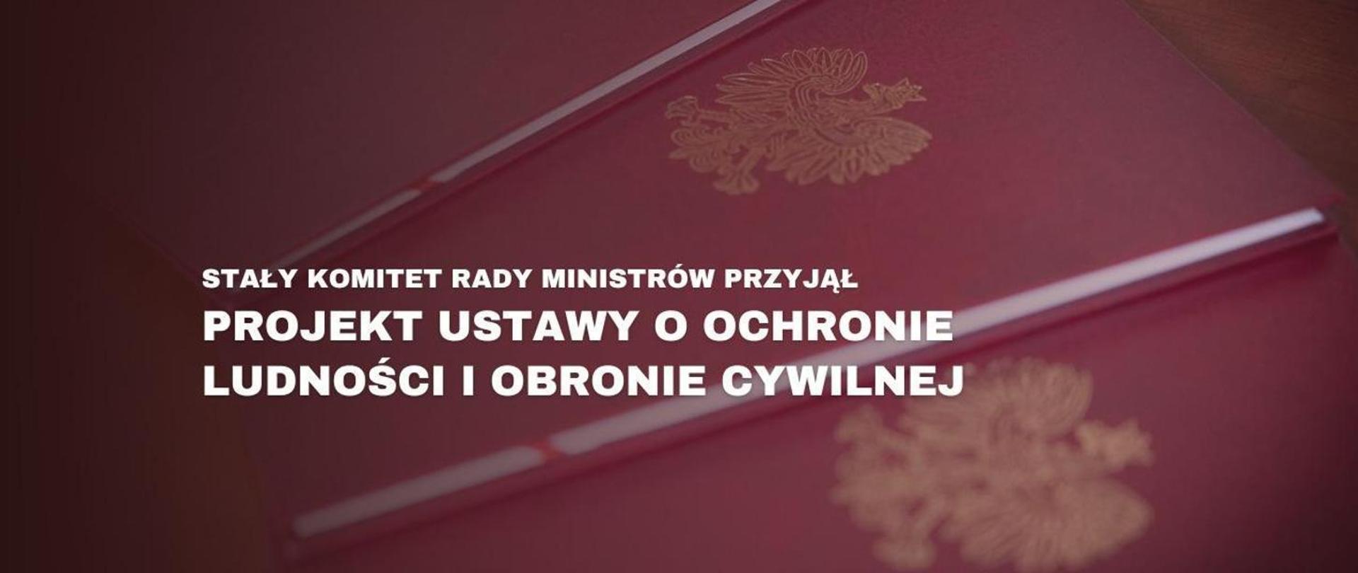 Czerwone teczki z orłem w tle. Na pierwszym planie napis Projekt ustawy o ochronie ludności i obronie cywilnej przyjęty przez Stały Komitet Rady Ministrów