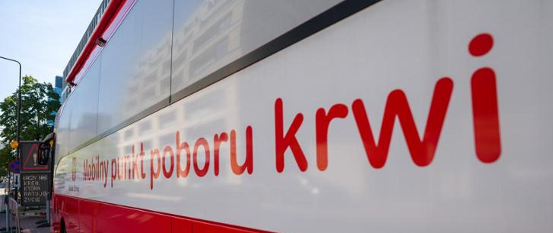 Bok autokaru - Mobilnego punktu poboru krwi. Autokar w kolorze biało czerwonym z widocznym napisem: Mobilny punkt poboru krwi.