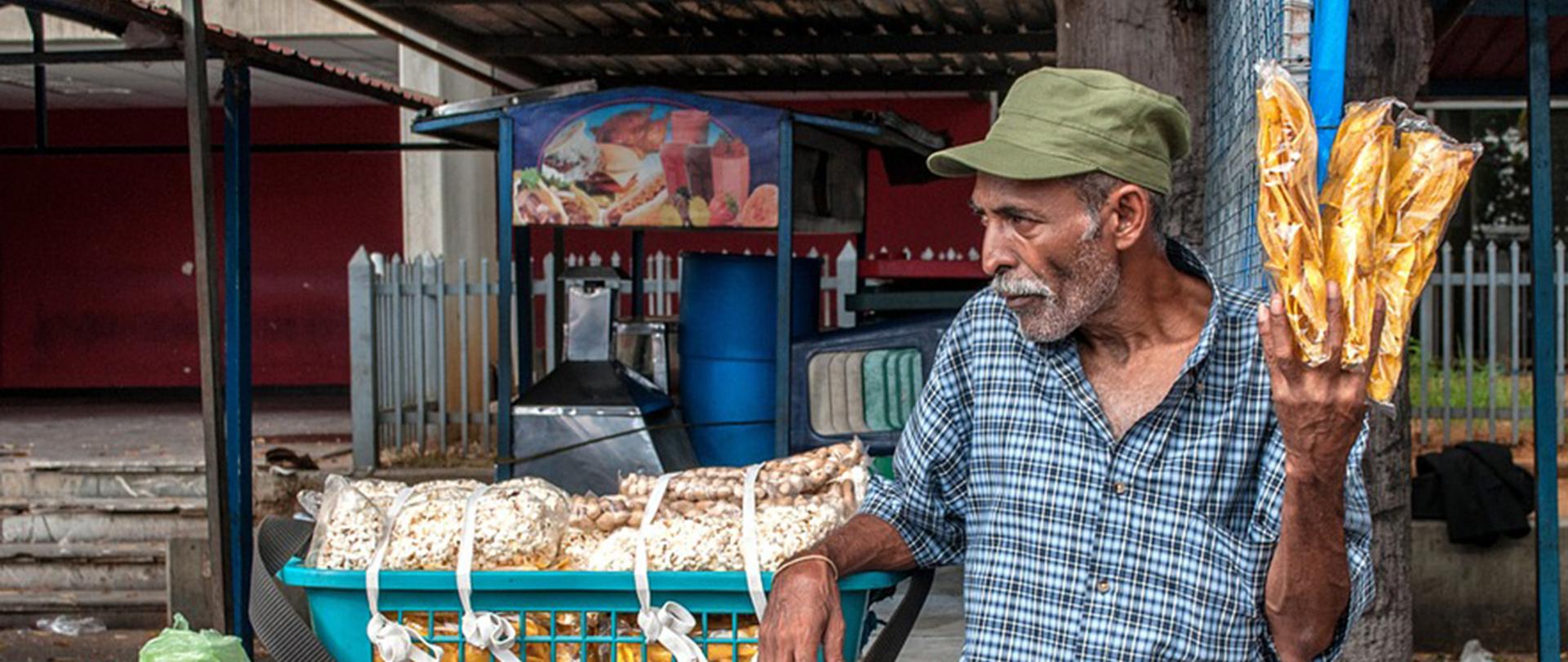 Zdjęcie poglądowe przedstawiające mężczyznę, który sprzedaje towary na targu