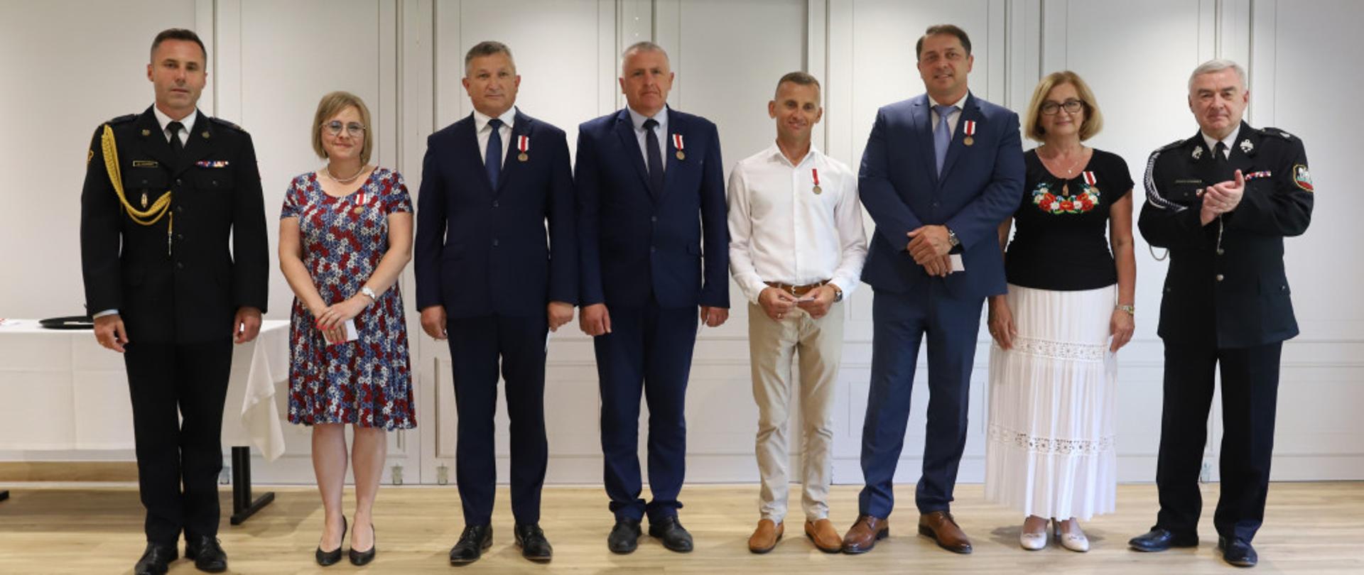 Zdjęcie przedstawia druhów OSP oraz osoby wspierające odznaczone medalami za zasługi dla pożarnictwa. 