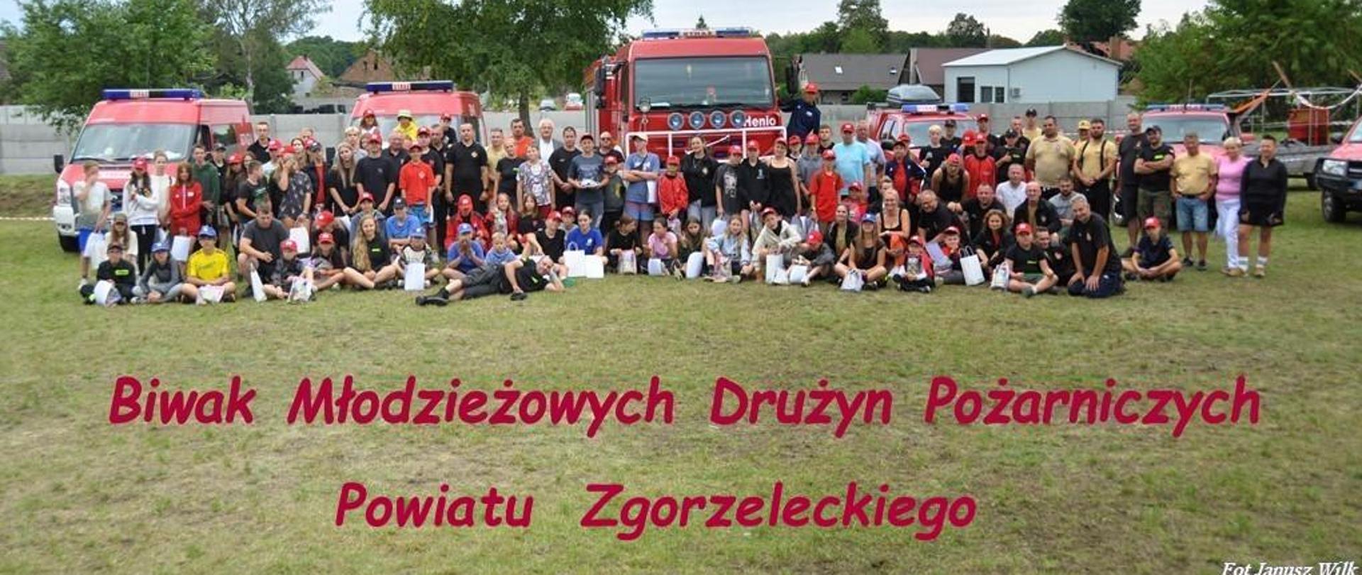 Dzień. Na tle kilku pojazdów ratowniczo-gaśniczych, do zdjęcia pozuje duża grupa dzieci oraz osób dorosłych